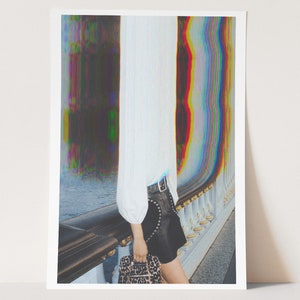 May include: A woman wearing a white shirt and a black mini skirt with silver studs stands on a bridge. She is holding a leopard print handbag. The background is a blurred image of a river and a bridge with a glitch effect.