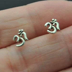 May include: A pair of silver earrings with a small Om symbol design.