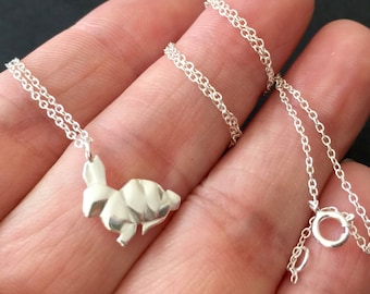 May include: A silver chain necklace with a silver origami rabbit pendant.