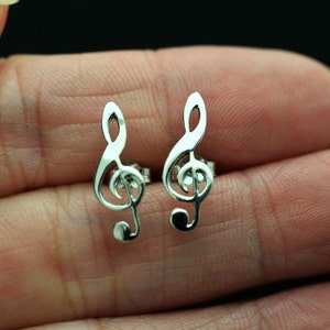May include: A pair of silver earrings shaped like treble clefs.