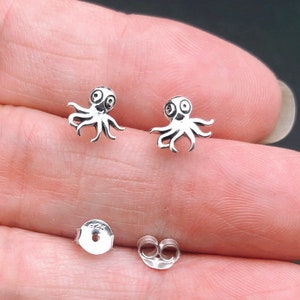 May include: A pair of silver octopus stud earrings. The octopus is a simple design with two eyes and eight tentacles.