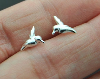 Könnte beinhalten: Ein Paar silberne Kolibri-Ohrringe. Die Ohrringe sind klein und zart und haben ein realistisches Kolibri-Design.
