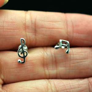 May include: A pair of silver earrings featuring a treble clef and a musical note.