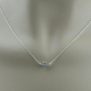 May include: A silver chain necklace with a small, delicate wing pendant.