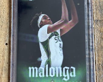 May include: A sports trading card featuring a basketball player in a white and green jersey with a headband, captured in a shooting motion. The card displays the text RYAN FORS, malonga, and DOMINIQUE CENTER, encased in a clear protective plastic sleeve.