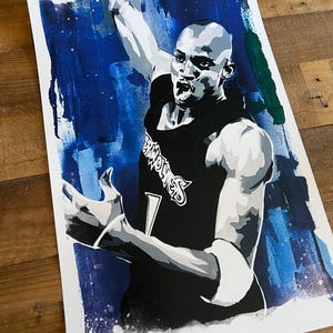 May include: A black and white illustration of a basketball player in mid-air, wearing a black jersey with the word "Wolves" on the front. The background is a blue and green watercolor wash.