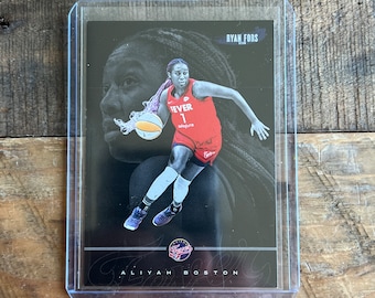 May include: A black and white basketball trading card featuring a female basketball player dribbling the ball. The card has a black background with a red and white basketball logo. The player is wearing a red jersey with the number 7 and the word "FEVER" on it. The card also includes the player's name, "Aliyah Boston", and the name of the card designer, "Ryan Fors".