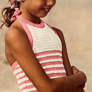 Könnte beinhalten: Eine junge Person trägt ein weiß-rosa gestreiftes Neckholder-Top und ein geblümtes Kopftuch. Das Top ist mit horizontalen Streifen gehäkelt. Das Kopftuch ist rot mit einem weißen Blumenmuster. Der Hintergrund ist eine Strandszene.