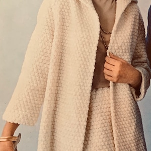May include: A white crocheted jacket and skirt set with a long-sleeved jacket and a knee-length skirt. The jacket has a hood and a collar. The skirt has a straight silhouette.