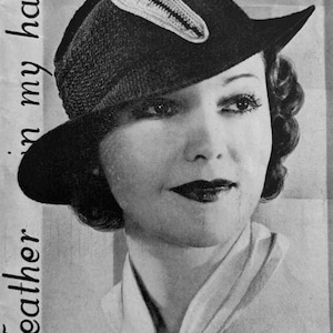 Op de afbeelding: Een zwart-witfoto van een vrouw die een zwarte hoed draagt met een witte verenversiering. De tekst "Feather in my hat!" staat links op de afbeelding.