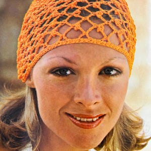 Może przedstawiać: Pomarańczowy kapelusz szydełkowy z siateczkowym wzorem. Kapelusz wykonany jest z teksturowanej przędzy i zakrywa górną część głowy. Kapelusz ma jasny, jednolity pomarańczowy kolor.