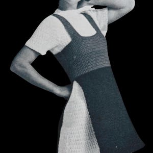 Pode incluir: Imagem a preto e branco de uma mulher a usar um vestido de croché. O vestido tem um corpete cinzento escuro e uma saia branca. A mulher está a usar um top branco de manga curta por baixo do vestido.