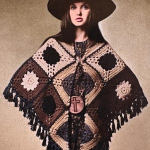 May include: A vintage-style crochet poncho in shades of brown, beige, and black, featuring a geometric pattern. The poncho has a fringe trim and a wooden cross pendant. A wide-brimmed hat completes the look.