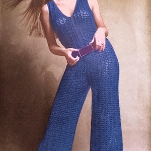 Peut inclure: Combinaison sans manches en crochet bleu avec un col en V et des jambes évasées. La combinaison est dotée d'une ceinture assortie et d'une fermeture éclair sur le devant. La modèle porte des chaussures noires. L'image a une esthétique vintage.