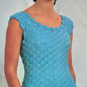 Könnte beinhalten: Eine Frau trägt ein ärmelloses, blaues Häkelkleid mit einem gewellten Ausschnitt. Sie trägt ein Perlenarmband am Handgelenk.