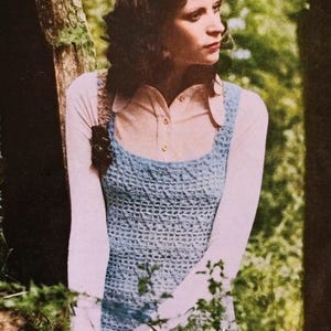 May include: A light blue crochet top with a square neckline is worn over a light pink collared shirt and white long-sleeved shirt. The image is set outdoors with a natural background. The text "MossandMoonbeam" is visible at the bottom.