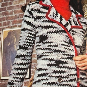 Puede incluir: Una chaqueta de crochet en blanco y negro con ribetes rojos. La chaqueta tiene un cierre de doble botonadura con botones plateados. El texto "BLAZING BORDERS Number GO-5" está en la parte superior de la imagen.
