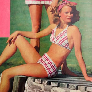 May include: A two-piece bikini set featuring a white knit fabric with a red plaid pattern. The top is a halter style with triangular cups, and the bottom is a high-waisted brief. A matching red fabric headband is worn around the head.