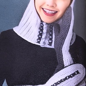 Pode incluir: Um conjunto de capuz, cachecol e luvas de crochê brancas e cinzentas. O capuz e as luvas têm um padrão listrado branco e cinzento com bordas decorativas. O cachecol tem um fecho de botão. O conjunto é feito de fio macio e texturizado.