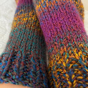 Puede incluir: Un par de calcetines de punto coloridos con un degradado de morado, naranja, azul y verde.
