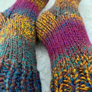 Puede incluir: Un par de calcetines de punto coloridos con un patr&oacute;n degradado en tonos de morado, azul, verde, marr&oacute;n y amarillo.