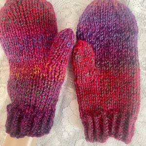 May include: A pair of knitted mittens in a gradient of pink, purple, and red.