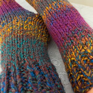 Puede incluir: Par de calcetines de punto coloridos con una mezcla de hilo morado, azul, verde, marr&oacute;n y amarillo.