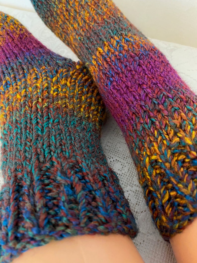 Puede incluir: Par de calcetines de punto coloridos con una mezcla de hilo morado, azul, verde, marr&oacute;n y amarillo.