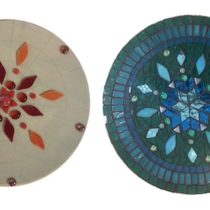 Puede incluir: Dos piezas redondas de arte en mosaico con un dise&ntilde;o de copo de nieve. Una es en tonos de rojo y naranja, la otra es en tonos de azul y verde.