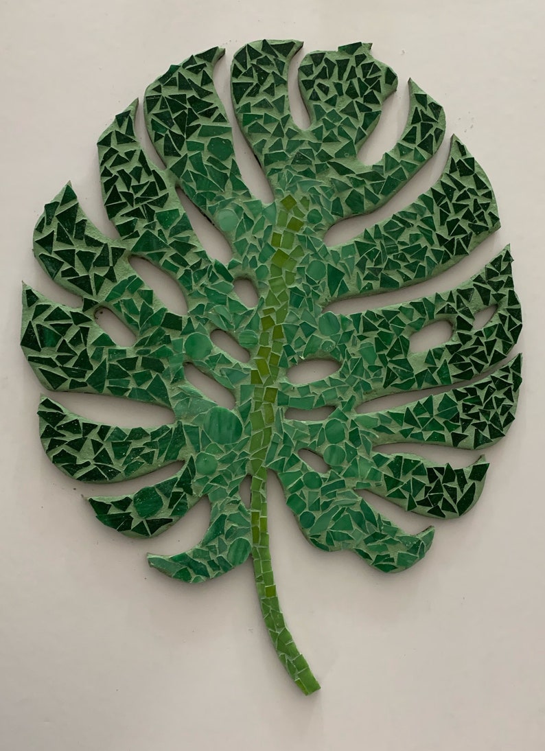 Puede incluir: Una hoja de mosaico verde con un dise&ntilde;o detallado. La hoja est&aacute; hecha de peque&ntilde;os trozos irregulares de vidrio verde.