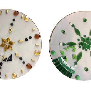Puede incluir: Dos bases redondas de madera sin terminar, blancas, con dise&ntilde;os de mosaico de azulejos. Una base tiene un dise&ntilde;o de estrella dorada con azulejos negros y marrones. La otra base tiene un dise&ntilde;o de copo de nieve verde.