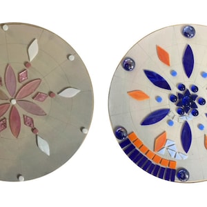 Puede incluir: Dos placas redondas de madera sin terminar con dise&ntilde;os de mosaico de azulejos. La primera placa tiene un dise&ntilde;o de flor rosa y blanca. La segunda placa tiene un dise&ntilde;o de flor azul y naranja.