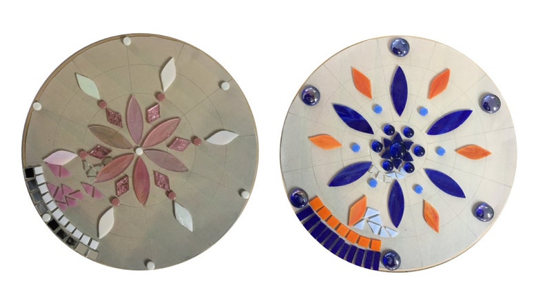 Puede incluir: Dos placas redondas de madera sin terminar con dise&ntilde;os de mosaico de azulejos. La primera placa tiene un dise&ntilde;o de flor rosa y blanca. La segunda placa tiene un dise&ntilde;o de flor azul y naranja.