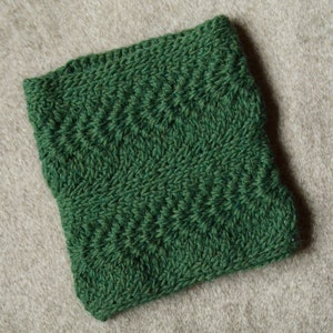 May include: A green knitted fabric with a textured pattern. The fabric is soft and has a subtle sheen.