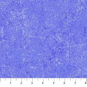May include: A close-up of a blue fabric with a textured, distressed appearance. The fabric has a mottled pattern with lighter blue and white accents, creating a worn, vintage aesthetic. A ruler is at the bottom, showing measurements in inches.