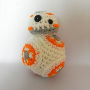 May include: A crocheted plush toy of BB-8 from Star Wars. The toy is white with orange and gray details. It has black button eyes.