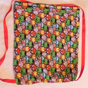 May include: A red drawstring bag with a black fabric featuring a repeating pattern of cartoon superhero characters. The characters include Iron Man, Captain America, Thor, Hulk, and Spiderman.