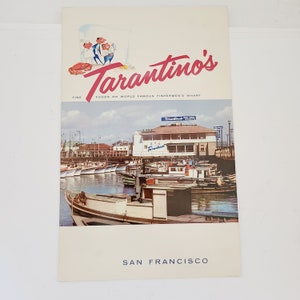 May include: A vintage postcard advertising Tarantino's Fine Foods on World Famous Fisherman's Wharf in San Francisco. The postcard features a colorful illustration of a restaurant building and boats docked at a pier.