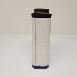 May include: White metal tin with a blue band around the top and bottom. The tin has a rusty metal lid.