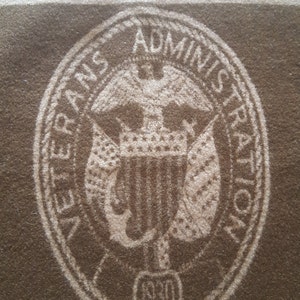 May include: A brown oval seal with the words "Veterans Administration" and "1930" in white lettering. The seal features a white eagle with a shield and a crown.