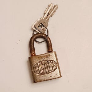 May include: A silver padlock with a brass keyhole and a silver key attached. The padlock has the word "BRISTOL'S" embossed on the front.