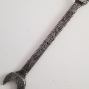 May include: A silver wrench with a 21B PLUMB MADE IN USA inscription. The wrench has a closed end and an open end.