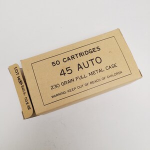 May include: A tan cardboard box labeled "50 CARTRIDGES 45 AUTO 230 GRAIN FULL METAL CASE." The box has a warning to keep out of reach of children and a lot number. The box is rectangular and has a partially open flap.