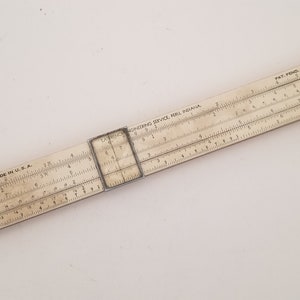 May include: A vintage white slide rule with the text "Computing Service, Inc. Pasadena" and "Pat. Pend." printed on it. The slide rule is made in the USA.
