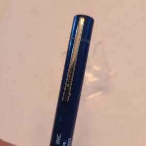 May include: A blue pen with a silver band and the word "FINESSE" engraved on it. The pen has the text "INC." and "352" printed on it.