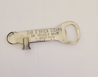 May include: Silver bottle opener with a built-in cigar cutter. The opener has the text "Dan O'Brien Cigars The Friendly Brand 40 Hedley Place Buffalo N.Y."