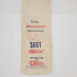 May include: A white canvas bag with red and blue text that reads "25 Lbs Winchester American Standard 9 Chill Shot Western Winchester-Western Division Olin Olin Mathieson Chemical Corporation New Haven, Conn, and East Alton, Ill."