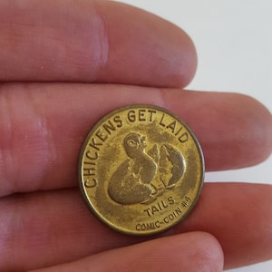 May include: A gold-colored coin with the text "Chickens Get Laid" and a cartoon image of two chickens. The coin also has the text "Tails Comic-Coin #4".
