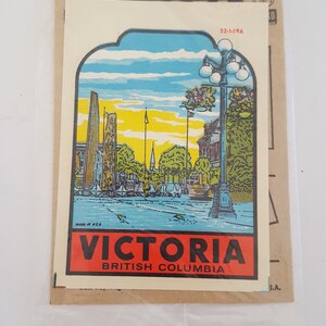May include: A vintage sticker featuring a colorful illustration of a cityscape with a street lamp and the text "VICTORIA BRITISH COLUMBIA".