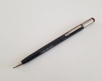 May include: A black mechanical pencil with a silver tip and clip. The pencil has the text "UNION 1968" printed on the side. The eraser is red. The pencil is lying on a white surface.